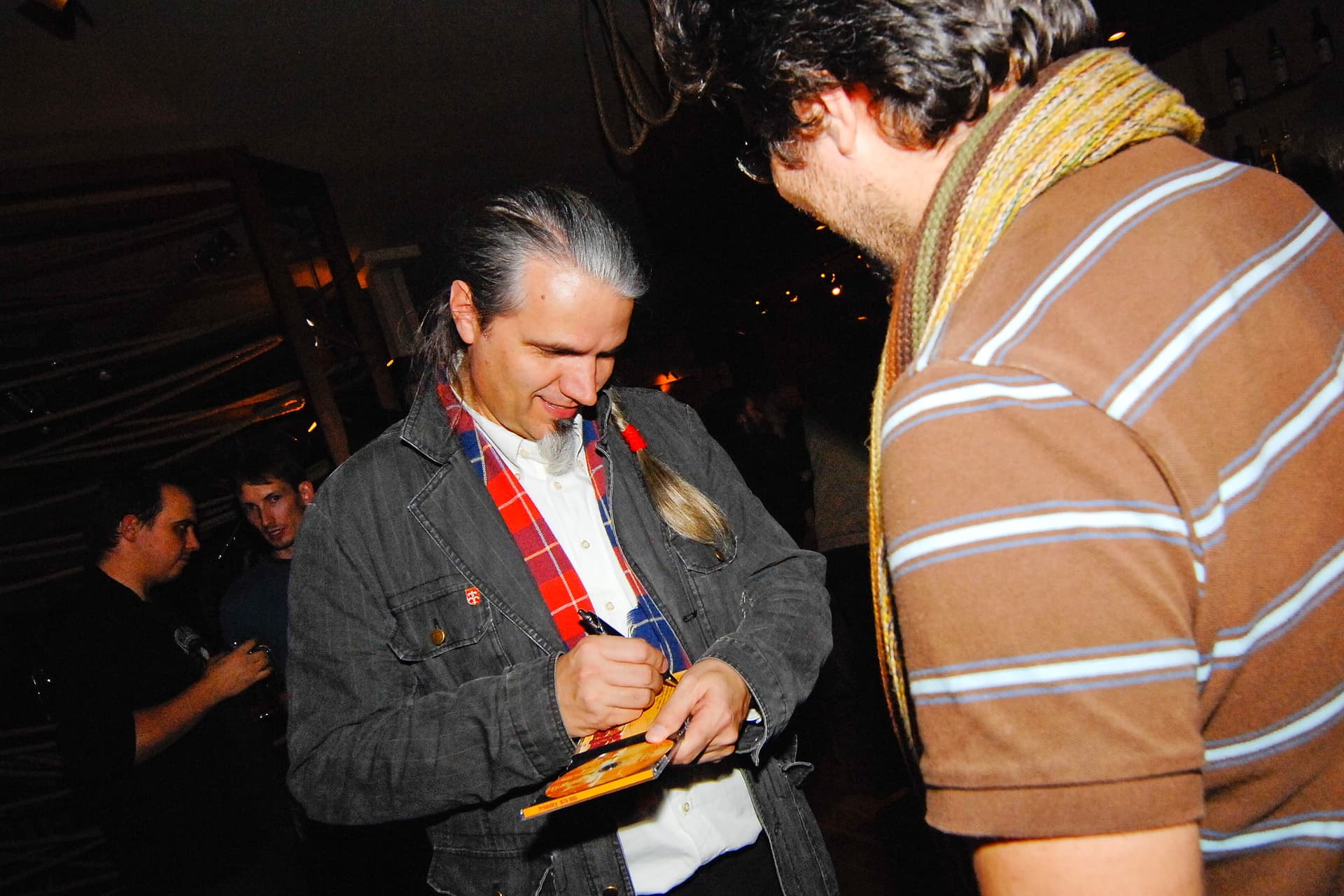 A podpis na CD. V pozadí vykukují nic netušící naši budoucí spoluhráči - basák a dobrista (Honza Panschab a Radek Vaňkát). (Teplice 2009)